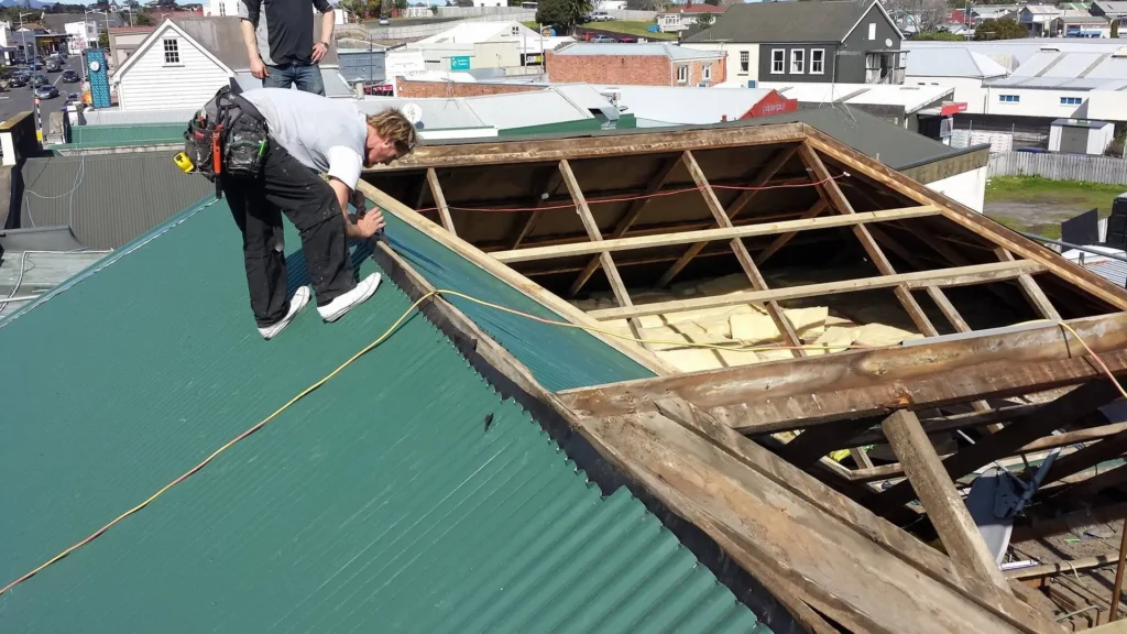 A Northland Roofing contractor secures new roofing sheets during a re-roofing project in progress.