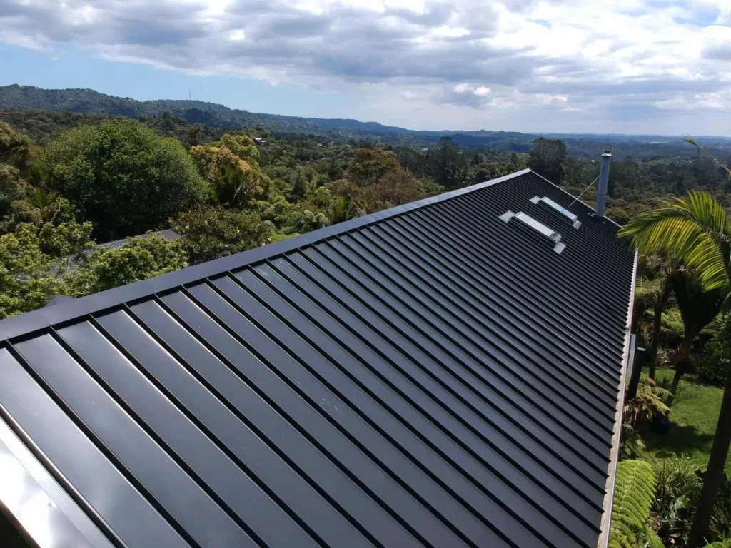 Long stretch of black standing seam metal roofing in a lush setting, expertly installed by Northland Roofing, learn more about us.