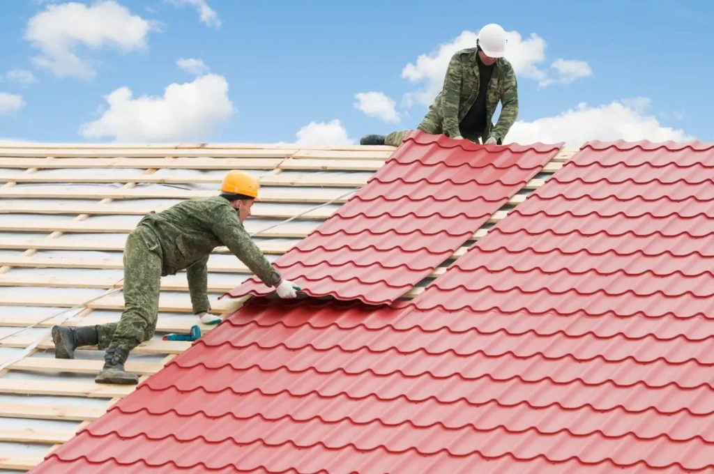 Two professionals installing bright red metal roofing sheets, a quality service from Northland Roofing.