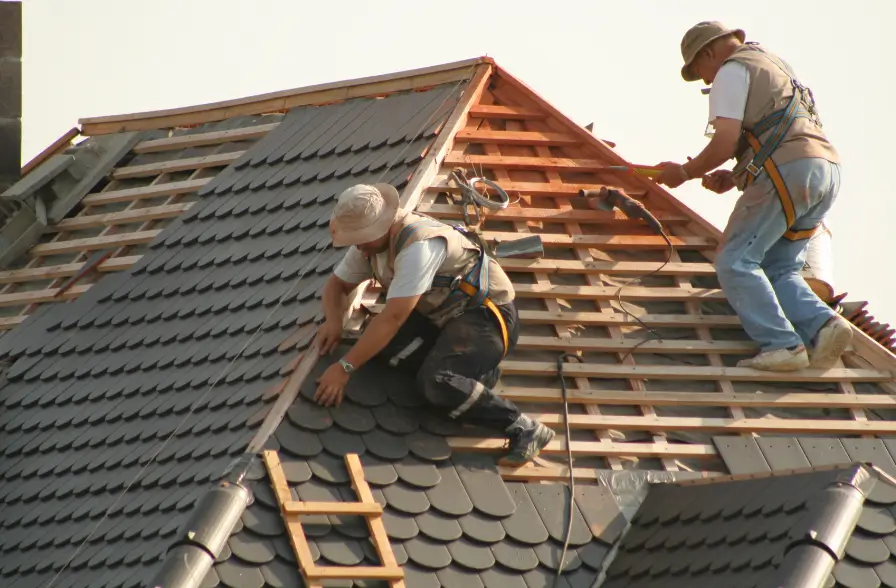 Two roofers securing slate shingles during a steep-pitch roof project for Northland Roofing roof repairs.