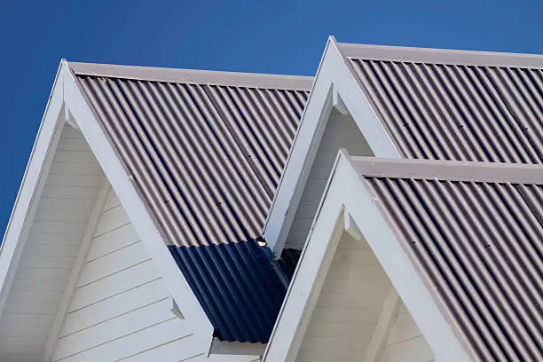 White gable rooflines with corrugated steel panels under a blue sky, a neat finish by Northland Roofing.