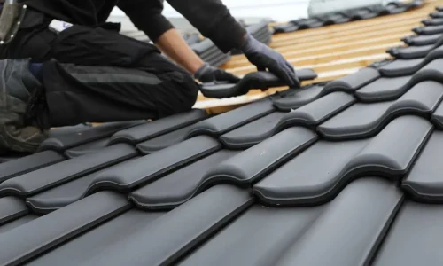 Precision tile placement during a Northland Roofing re-roofing project using dark roofing tiles.